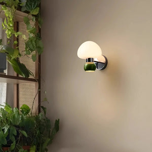 Wall-mounted lamp with a round white glass shade and green metal base.