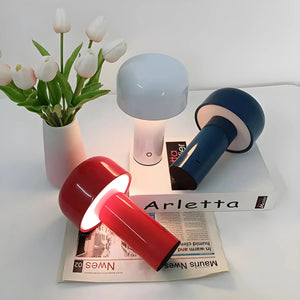 Collection of modern desk lamps in various colors alongside a vase of white tulips.