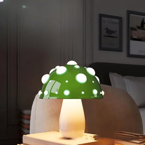 Whimsical mushroom-shaped table lamp with a green cap dotted with white spots.