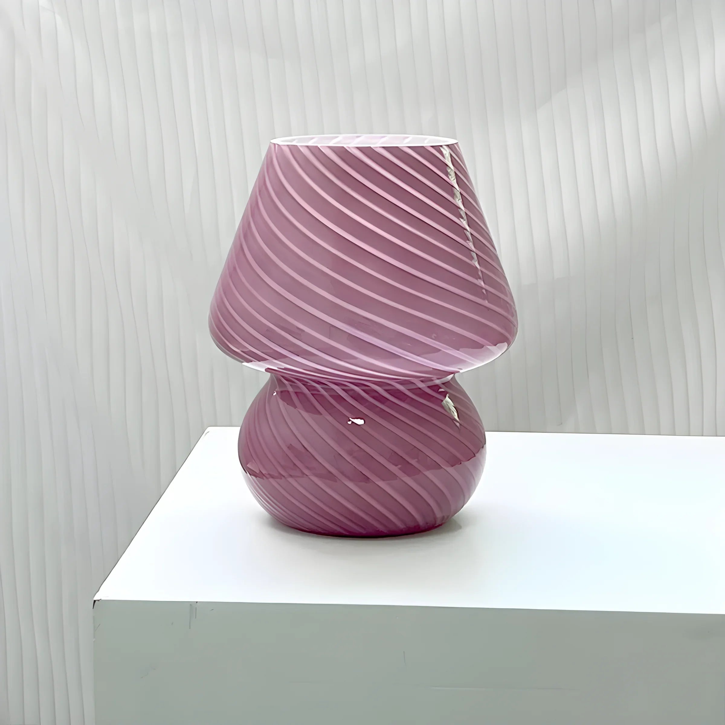 Pink glass table lamp with swirled pattern.