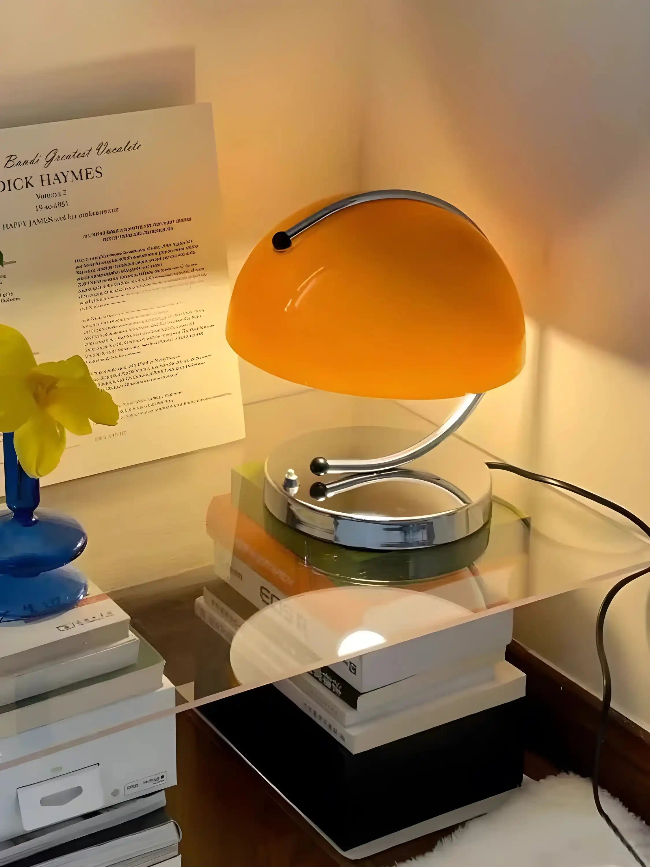 Retro-style desk lamp with an orange dome shade and curved chrome arm.