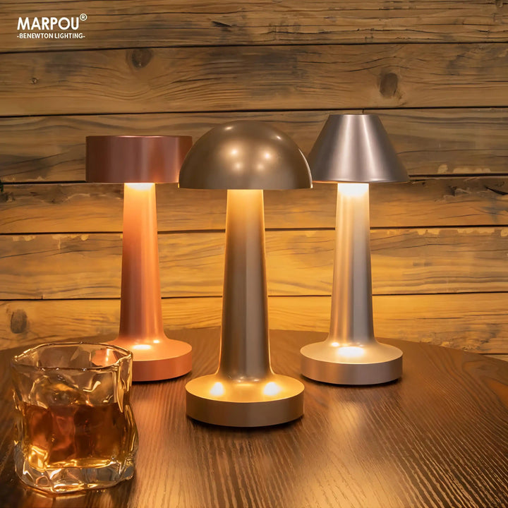 Set of three modern, cordless table lamps with mushroom-shaped designs in different metallic finishes.