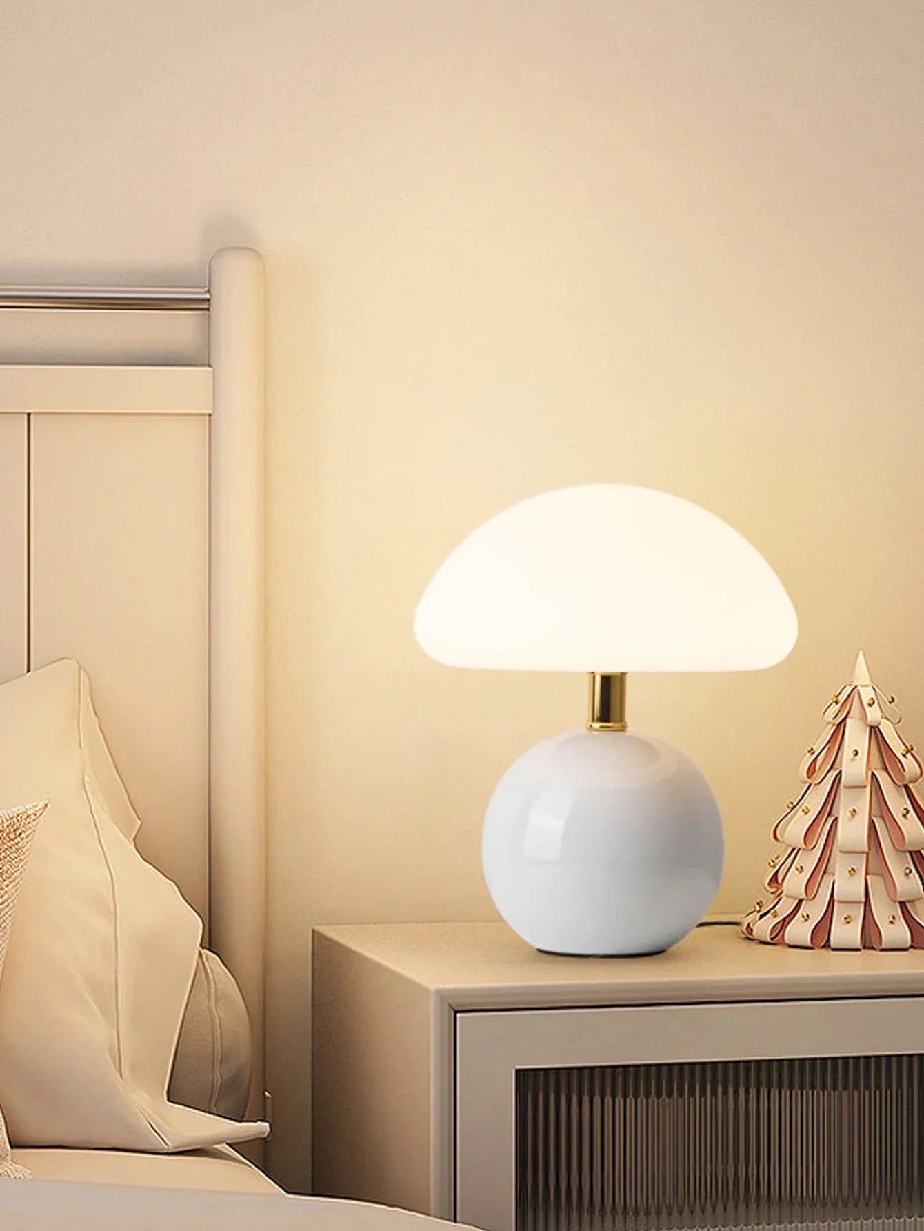 Spherical white table lamp with a domed shade emitting warm light.