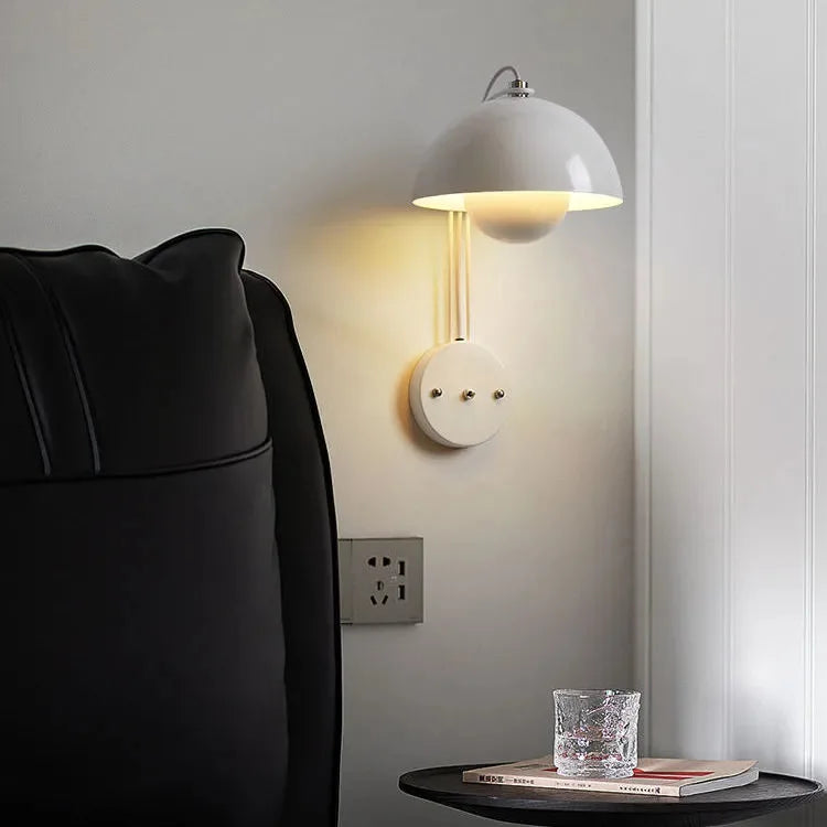 Wall-mounted lamp with a white dome shade and circular base containing electrical outlets.