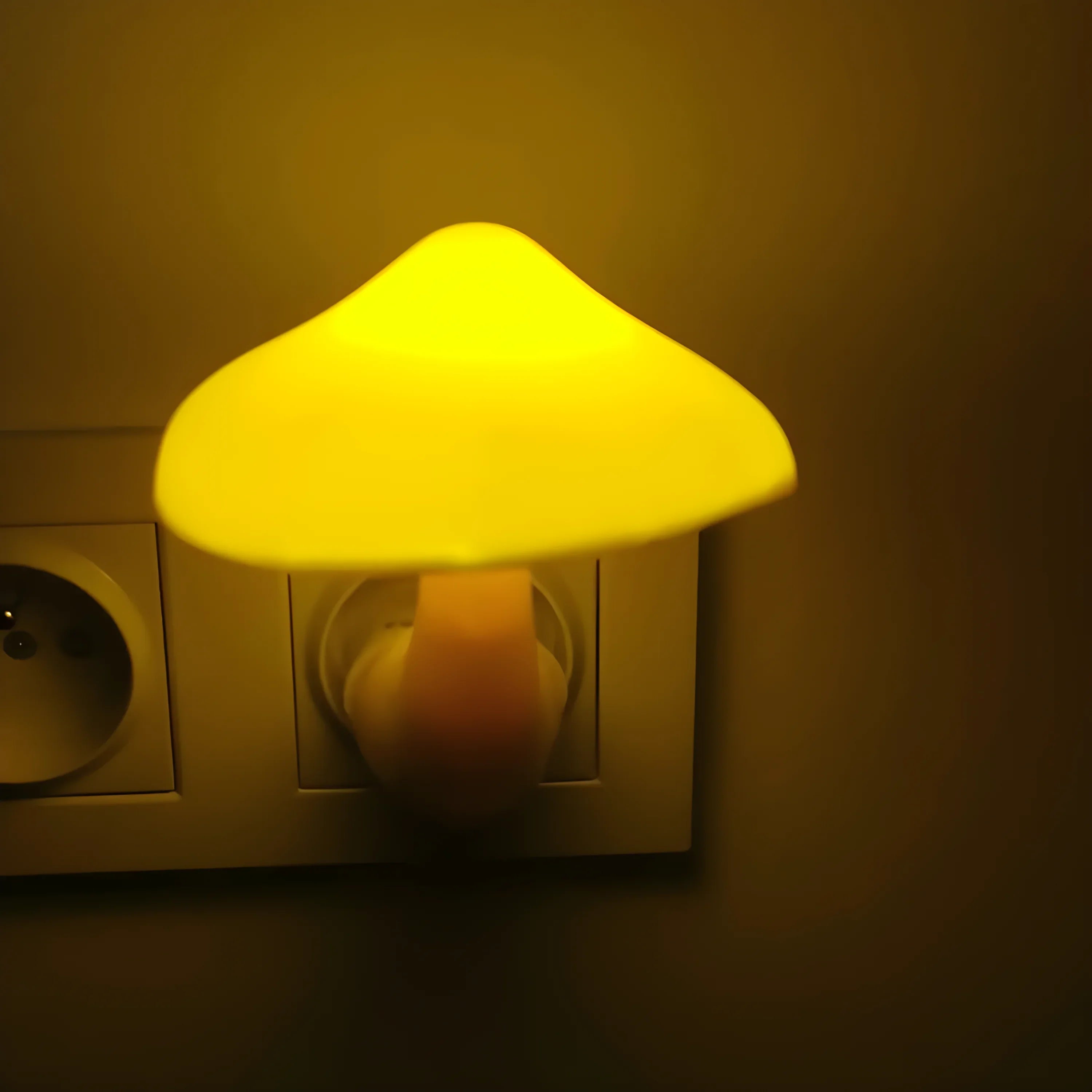 Yellow mushroom-shaped night light plugged into an electrical outlet.